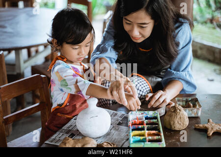 Fille apprentissage de peinture la couleur avec les conseils de sa mère Banque D'Images