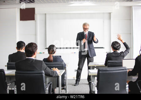 L'auditoire d'élever jusqu'à la main tout en parlant d'affaires est en formation pour avis à l'animateur dans la salle de conférence Banque D'Images