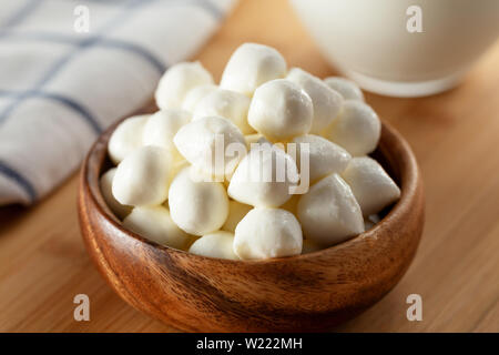 Boules de fromage mozzarella dans un bol et verre de lait sur fond de bois Banque D'Images