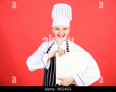 Femme au foyer avec livre de cuisine. happy woman cooking alimentation saine par recette. chef professionnel en cuisine. Cuisine. menu du restaurant. Suivre un régime culinaire. femme dans cook hat et tablier. Look sympathique. Banque D'Images