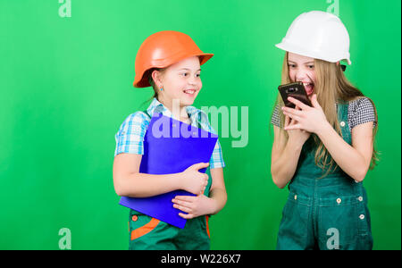 La fête du travail. 1 mai. Projet d'école. Inspecteur de contremaître. La réparation. Les petits enfants en casque avec tablette. petites filles réparer ensemble en atelier. crier sur travailleur dans l'appel téléphonique. discuter de problèmes. Banque D'Images