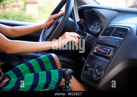 Jeune femme démarre le moteur de la voiture. Banque D'Images