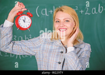 Maître de l'école de fille. Quelle heure est-il. Horaire des leçons. Enseignants bienvenue année scolaire. Santé et régime quotidien. Leçon de début d'éducateur. Elle se soucie de la discipline. Enseignant femme tenir réveil. Banque D'Images