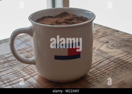 Orlando, Floride. Le 6 juin 2019 . Tommy Hilfiger tasse avec du café moulu sur table rustique en bois au Premium Outlet dans International Drive Area . Banque D'Images