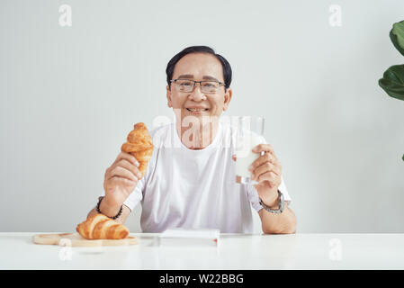 Petit-déjeuner à matin. La personne tenant un croissant avec le verre de lait. Alimentation saine. Banque D'Images