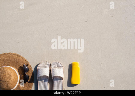 Vacances d'été : concept, espadrilles crème protectrice et un chapeau sur le sable propre. Vue de dessus accessoires pour vacances à la mer avec copie espace naturel Banque D'Images