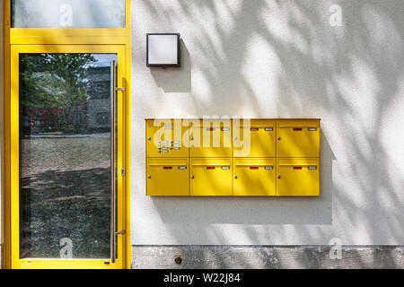 Immeuble d'habitation moderne entrée avec porte en verre, boîtes aux lettres jaune et l'ombre des arbres sur le mur. Nouvelle maison en construction Banque D'Images