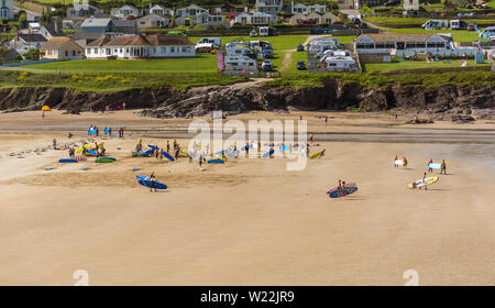 Les surfeurs se diriger vers la mer, sur la plage de Polzeath à North Cornwall, UK. Prise le 27 juin 2019. Banque D'Images