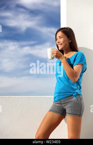 Café du matin, petit-déjeuner en yoga woman activewear à la maison piscine terrasse salon. Asian fitness fit girl drinking profiter de soleil de l'été à l'extérieur après l'exercice d'entraînement. Mode de vie sain et actif. Banque D'Images