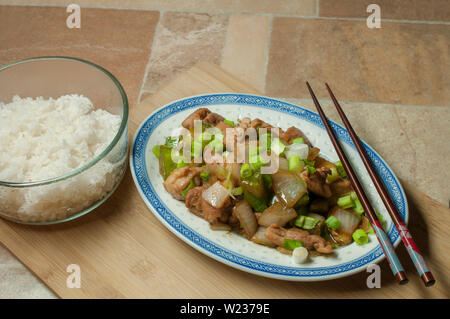 Poulet aux poivrons, oignons, ciboulette et avec de la sauce soja sur une planche à découper en bois, cuisine traditionnelle Asiatique Banque D'Images