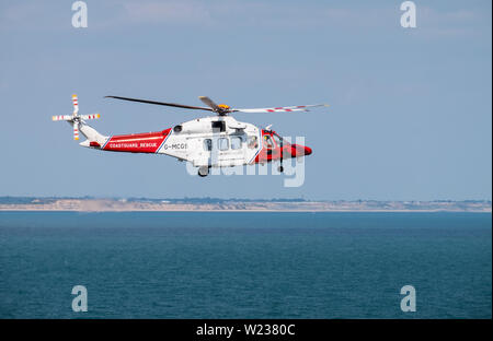 HM Coastguard Hélicoptère survolant la côte du Dorset Banque D'Images