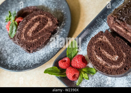 Swiss roll avec de la confiture au chocolat décoré avec des framboises dans une assiette. Des bonbons. Focus sélectif. Banque D'Images