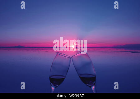 Deux verres de trinquer à l'occasion de le coucher du soleil sur l'inondation des marais salants, Uyuni, Bolivie Banque D'Images