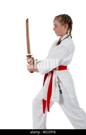 Pre-teen caucasian girl portant un uniforme de karaté kata effectuant une épée en bois avec une épée de formation Banque D'Images