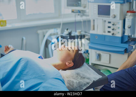 Plusieurs médecins entourant patient sur table d'opération pendant leur travail. Les chirurgiens de l'équipe au travail en salle d'opération. Banque D'Images