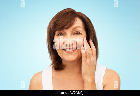 Portrait of smiling senior woman touching her face Banque D'Images