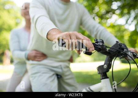 Happy senior couple riding un vélo à park Banque D'Images
