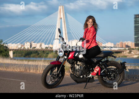 Jeune femme assise sur une moto rouge Banque D'Images