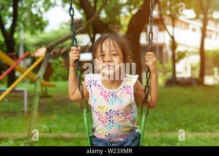 Asian girl sur une balançoire en souriant. Filipina kid playing in park. Banque D'Images