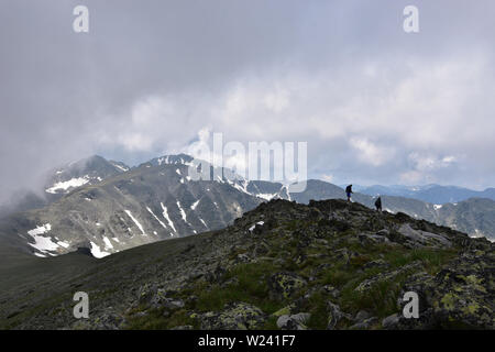 Des silhouettes lointaines de deux hommes en montagne. Temps extrême avec nuages de tempête sur Deno Peak, Rila Mountain, Bulgarie Banque D'Images