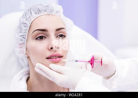 Dermatologue injecting botox injection on woman's lips, close-up. Banque D'Images