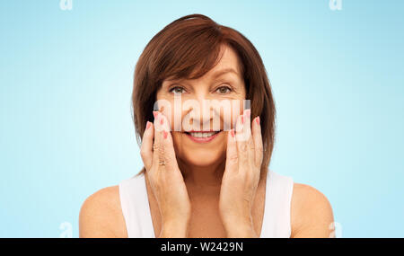 Portrait of smiling senior woman touching her face Banque D'Images