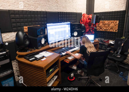 Musicien de sexe féminin travaillant dans un studio d'enregistrement de la musique moderne. jouer sur clavier et travailler avec un logiciel d'enregistrement d'une modification de la musique sur grand écran Banque D'Images