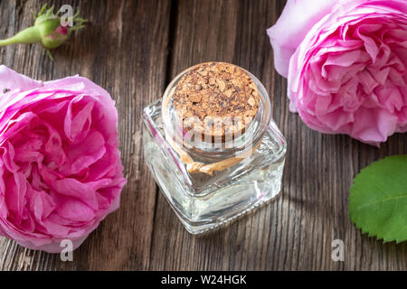 Un flacon carré d'huile essentielle de Rose de mai des fleurs sur une table Banque D'Images