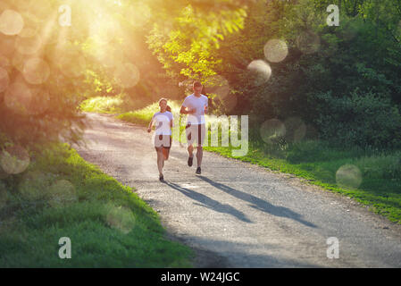 Les jeunes et l'exercice de jogging dans la nature, dans le soleil levant lumière chaude Banque D'Images