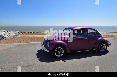 Violet classique VW Coccinelle Voiture moteur en roulant le long de la promenade. Banque D'Images