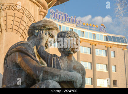 SKOPJE, Macédoine DU NORD/Août 22 2018 : Statue d'Alexandre le Grand comme un enfant avec sa mère est assise près de l'hôtel Stone Bridge (arrière-plan),Skopj Banque D'Images