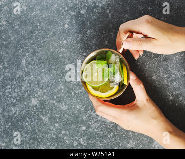 Woman's hands holding une tasse de cuivre de limonade à la menthe fraîche, vue du dessus, copy space Banque D'Images