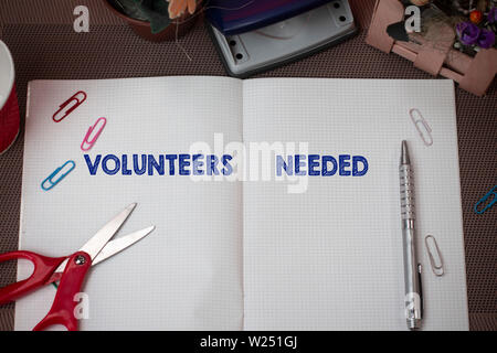 Écrit remarque montrant les bénévoles nécessaires. Concept d'affaires pour travailler ou besoin d'aide pour l'Organisation sans être payés et l'écriture Ciseaux plu équipements Banque D'Images