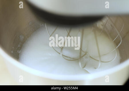 Les blancs d'œufs en fouettant mélangeur de cuisine professionnel dans un restaurant. Close-up fouetté les blancs et le sucre dans un bol mélangeur planétaire de métal. Banque D'Images