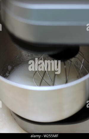 Les blancs d'œufs en fouettant mélangeur de cuisine professionnel dans un restaurant. Close-up fouetté les blancs et le sucre dans un bol mélangeur planétaire de métal. Banque D'Images
