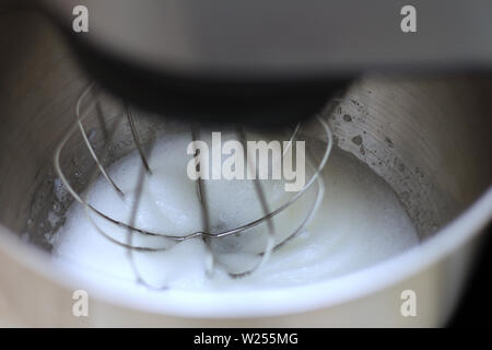 Les blancs d'œufs en fouettant mélangeur de cuisine professionnel dans un restaurant. Close-up fouetté les blancs et le sucre dans un bol mélangeur planétaire de métal. Banque D'Images