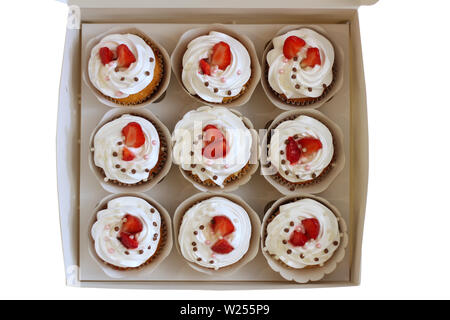 Close-up cupcakes avec de la crème fraîche oeufs décorés de fraises et chocolat balls dans du papier blanc fort Banque D'Images