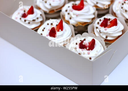 Close-up cupcakes avec de la crème fraîche oeufs décorés de fraises et chocolat balls dans du papier blanc fort Banque D'Images