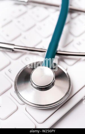 Stéthoscope sur clavier d'ordinateur sur fond blanc. Écrire un médecin de soins de longue durée de cas médicaux, traitement notion close up, macro, copy space Banque D'Images