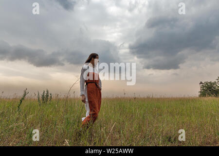 KHORTYTSIA, UKRAINE - Juillet 03, 2018 : blanc femme en robe médiévale marche dans la steppe avec thunder ciel été paysage sur Khortytsia isl Banque D'Images