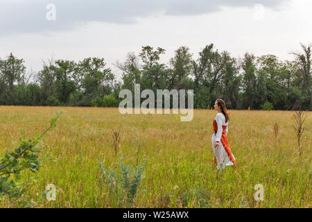 KHORTYTSIA, UKRAINE - Juillet 03, 2018 : blanc femme en robe médiévale marche dans la steppe avec thunder ciel été paysage sur Khortytsia isl Banque D'Images