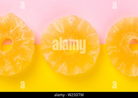 Ananas séché candy sonne, dans du sucre en poudre, sur un fond jaune-rose Banque D'Images