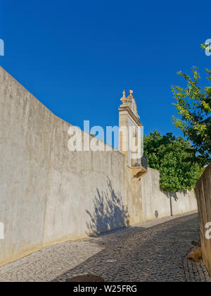 Une petite terrasse avec fer forgé donnant sur une petite rue pavée en dessous des murs du palais de Estoi en Algarve au Portugal. Banque D'Images