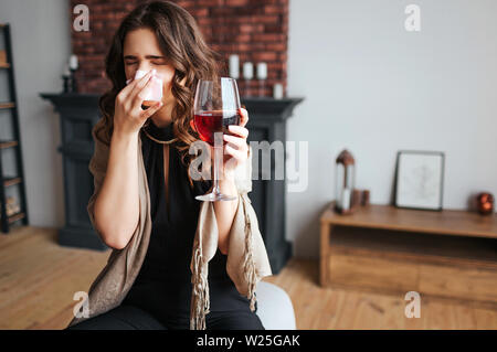 Young businesswoman travailler à la maison. Modèle de maladie maintenir le verre de vin rouge dans la main. Couvrir de tissus du nez. Malade malade femme froid et virus. La maladie Banque D'Images