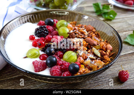 Yaourts, céréales, fruits frais dans un bol sur une table en bois. Petit-déjeuner délicieux et sains. Une bonne nutrition. Menu diététique. Banque D'Images