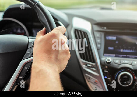 Détail de l'homme main sur le volant, une partie de voiture visible de l'intérieur, vue depuis le siège passager Banque D'Images