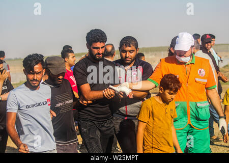 5 juillet 2019 - Gaza, Palestine. 05 juillet 2019. Des manifestants palestiniens en conflit avec les forces israéliennes au cours de ce vendredi est une grande marche du retour dans la région de Malika sur l'est de la ville de Gaza. Des milliers de Palestiniens avait convergé sur différents sites à proximité de la frontière Gaza-Israel à rejoindre les manifestations. Certains des manifestants ont lancé des pierres vers les soldats israéliens stationnés sur l'autre côté de la clôture qui ont répondu avec des gaz lacrymogènes et des balles réelles blessant des dizaines de manifestants palestiniens. Des manifestants palestiniens ont organisé une grande marche du retour manifestations depuis le 30 mars l'année dernière Banque D'Images