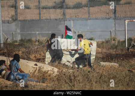 5 juillet 2019 - Gaza, Palestine. 05 juillet 2019. Des manifestants palestiniens en conflit avec les forces israéliennes au cours de ce vendredi est une grande marche du retour dans la région de Malika sur l'est de la ville de Gaza. Des milliers de Palestiniens avait convergé sur différents sites à proximité de la frontière Gaza-Israel à rejoindre les manifestations. Certains des manifestants ont lancé des pierres vers les soldats israéliens stationnés sur l'autre côté de la clôture qui ont répondu avec des gaz lacrymogènes et des balles réelles blessant des dizaines de manifestants palestiniens. Des manifestants palestiniens ont organisé une grande marche du retour manifestations depuis le 30 mars l'année dernière Banque D'Images