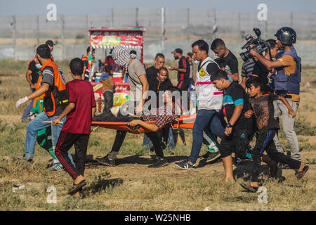 5 juillet 2019 - Gaza, Palestine. 05 juillet 2019. Des manifestants palestiniens en conflit avec les forces israéliennes au cours de ce vendredi est une grande marche du retour dans la région de Malika sur l'est de la ville de Gaza. Des milliers de Palestiniens avait convergé sur différents sites à proximité de la frontière Gaza-Israel à rejoindre les manifestations. Certains des manifestants ont lancé des pierres vers les soldats israéliens stationnés sur l'autre côté de la clôture qui ont répondu avec des gaz lacrymogènes et des balles réelles blessant des dizaines de manifestants palestiniens. Des manifestants palestiniens ont organisé une grande marche du retour manifestations depuis le 30 mars l'année dernière Banque D'Images