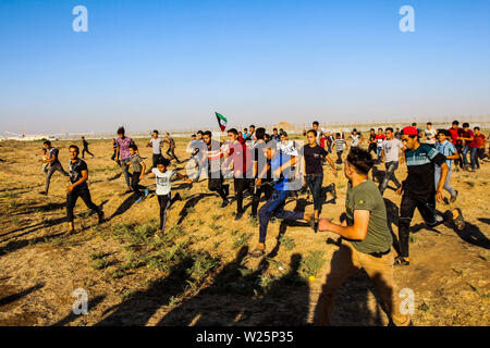 5 juillet 2019 - Gaza, Palestine. 05 juillet 2019. Des manifestants palestiniens en conflit avec les forces israéliennes au cours de ce vendredi est une grande marche du retour dans la région de Malika sur l'est de la ville de Gaza. Des milliers de Palestiniens avait convergé sur différents sites à proximité de la frontière Gaza-Israel à rejoindre les manifestations. Certains des manifestants ont lancé des pierres vers les soldats israéliens stationnés sur l'autre côté de la clôture qui ont répondu avec des gaz lacrymogènes et des balles réelles blessant des dizaines de manifestants palestiniens. Des manifestants palestiniens ont organisé une grande marche du retour manifestations depuis le 30 mars l'année dernière Banque D'Images